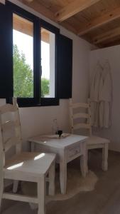 アラウリン・エル・グランデにあるFinca Rayo del Solのテーブルと椅子2脚、窓が備わる客室です。