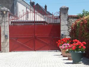 a red gate with red flowers in pots at Les 4 vents in Vineuil