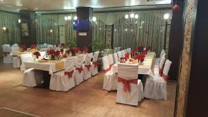 une salle à manger avec des tables blanches et des archets rouges dans l'établissement Hotel Alegra, à Velingrad