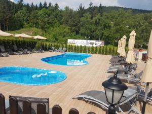 a pool with chairs and umbrellas on a patio at Hotel Alegra in Velingrad