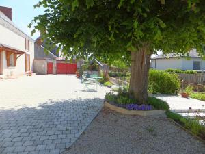 a tree in a courtyard with a table and purple flowers at Les 4 vents in Vineuil