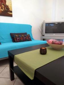 ネア・スキオニにあるRoses RT apartments Skioni IIのリビングルーム(青いソファ、テーブルの上にボウル付)