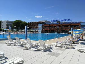 a pool with chairs and umbrellas and people in a resort at Condominio Moschettieri in Bibione