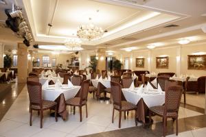 a restaurant with white tables and chairs and a chandelier at Relita-Kazan Hotel in Kazan