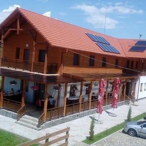 a large wooden building with a solar roof with a car at Vila Lorin in Cristeştii Ciceiului