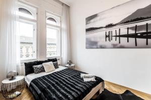 1 dormitorio con 1 cama y una pintura en la pared en BpR Luxe de Noir et Blanc Apartment en Budapest