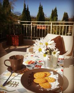 a table with a plate of cookies and flowers on it at Vikeya Guest House in Sapareva Banya
