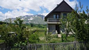 a house with a fence and mountains in the background at Kovcica Rooms in Žabljak