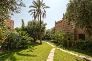ogród z palmą i budynek w obiekcie Villa Touareg Domaine des Kasbahs w Marakeszu