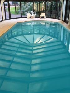 a pool with blue water and two chairs in it at Maison Dans Le Parc Du Château in Larçay