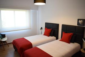 Duas camas com almofadas vermelhas num quarto em Casa Lisboa Oriente em Lisboa