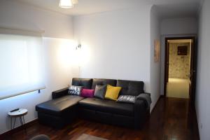 uma sala de estar com um sofá de couro preto com almofadas coloridas em Casa Lisboa Oriente em Lisboa