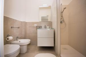a white bathroom with a sink and a toilet at Mariú Rooms in Castellammare del Golfo +36 photos