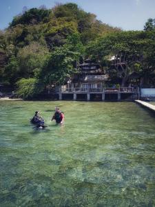 two people are in the water near a beach at Casita Ysabel in Mabini