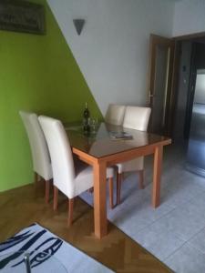 uma sala de jantar com uma mesa de madeira e cadeiras brancas em Apartment Ivan em Trogir