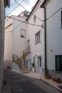 a white building with stairs in a street at Apartments Tara in Vrbnik