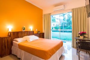 a bedroom with a bed and a large window at Pousada Villa Piemonte in Ubatuba