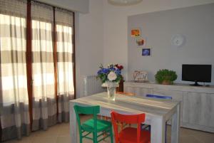 een eettafel met 4 stoelen en een vaas met bloemen bij La Casa Di Astorre in Bettolle
