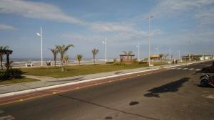 a road with a beach with palm trees and a motorcycle at Capao Canoa - Próximo Mar Centro in Capão da Canoa