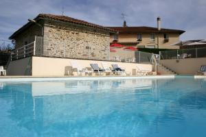 a large swimming pool with chairs and a building at Maison de Vacances Le Ranfort in Sousceyrac