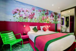 a bedroom with a pink bed and a green chair at Jardins de Montmartre in Paris