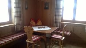 a table and two chairs in a room with windows at Ferienhaus Egger in Innervillgraten