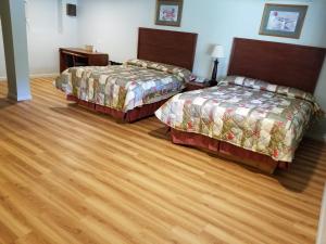 a hotel room with two beds and wooden floors at Wolds Motel - Mt. Pleasant in Mount Pleasant