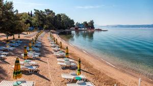 a beach with chairs and umbrellas and the water at Apartments Karalic in Crikvenica