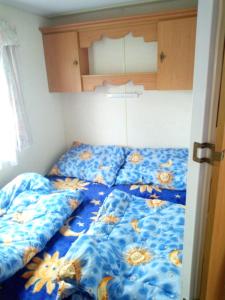 a bed with a blue bedspread with flowers on it at Ubytovani v mobilnim domku in Sobotka