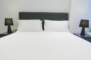 a bedroom with a large bed with two lamps at Comfy Studio 6 by ReCharge in Singapore