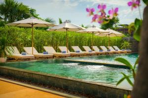 a swimming pool with lounge chairs and umbrellas at Khmer House Resort in Siem Reap