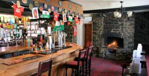 a bar with chairs and a fireplace in a restaurant at Belle Vue Hotel in Llanwrtyd Wells