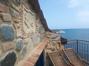 un mur en pierre avec deux bancs près de l'océan dans l'établissement Casa il Soffio di Eolo, à Scilla