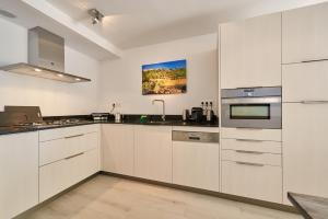 una cocina con armarios blancos y fregadero en Residence Velas Garden Pool Suite, en S'Agaró