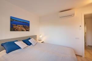 a bedroom with a large bed with blue pillows at Residence Velas Garden Pool Suite in S'Agaro +16 photos