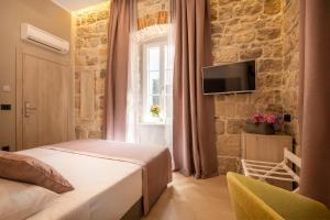 a bedroom with a bed and a tv on a stone wall at Boutique B&B Villa Faggioni in Cavtat