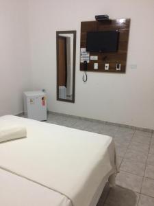 a room with a bed and a tv on a wall at Hotel Mirante do Vale in Itabaiana