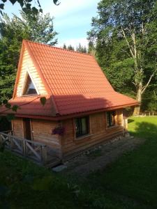 une petite cabane en bois avec un toit orange dans l'établissement Magellan Domki, à Cisna