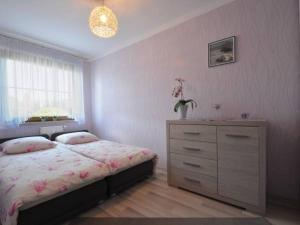 sypialnia z łóżkiem, komodą i oknem w obiekcie Apartament na Jagiellońskiej w Kołobrzegu