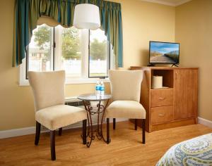 1 dormitorio con 2 sillas, mesa y TV en Breezeway Resort, en Westerly