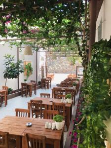 un restaurante con mesas de madera, sillas y plantas en Kekik Butik Otel, en Cesme