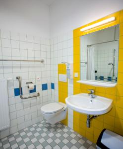a bathroom with a sink, toilet, mirror and tub at Haus Mobene - Hotel Garni in Graz