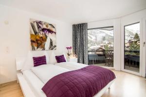 a white bedroom with a purple bed and a balcony at Haus Allegra in Saas-Fee