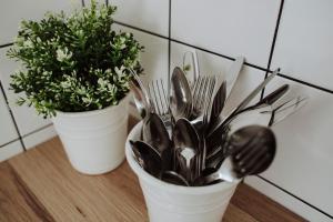 two white containers filled with spoons and forks and a plant at Śpij w Nysie Apartments in Nysa