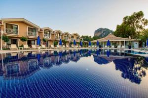 una piscina en un complejo con sillas y sombrillas en Dalyan Resort & Spa, en Dalyan