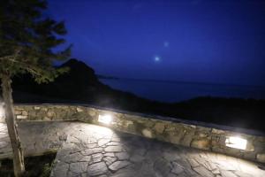 a night view of the ocean and a stone wall at Skouros Villa in Kastrí