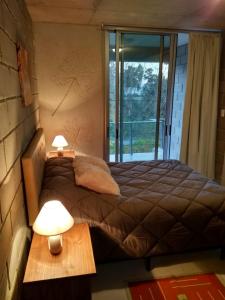 1 dormitorio con 1 cama con 2 lámparas y una ventana en I+O "Inside and out", en Colonia del Sacramento