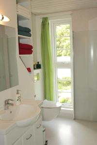 a bathroom with a sink and a toilet and a window at Tvillinggaard Thy in Vang