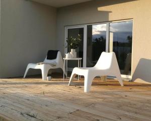 two white chairs sitting in a room with a window at Dru-Sky in Druskininkai