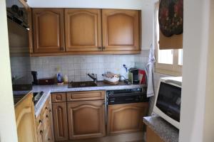 een keuken met houten kasten, een wastafel en een fornuis bij Chalet Le Slalom in Arveyes